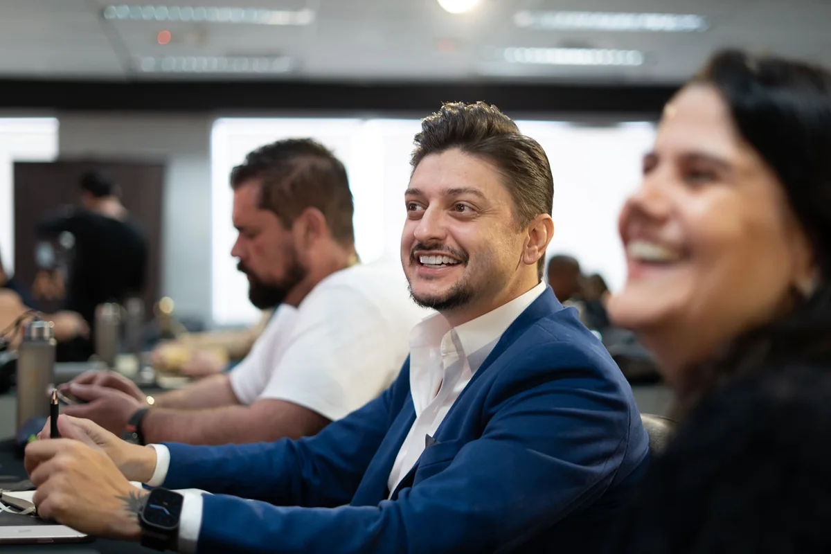 Reunião comercial em volta da mesa, com o time acompanhando